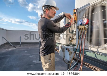 HVAC technician looking at his multimeter reading while testing voltage to a mini split air conditioning system. Stock photo © 