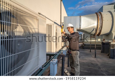 HVAC technician servicing commercial air conditioning equipment on building roof top Stock photo © 
