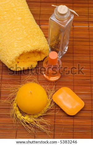 Spa scenery: yellow towel, candle, soap, fragrance and amber.