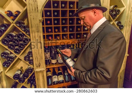 Jefferson, TX, USA - December 20: Elegant senior in a expensive wine storage in a expensive multi-million house choosing right wine.