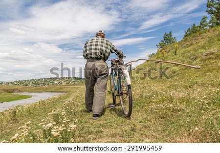 Trebujeni, Moldova - June 27, 2015: Old man is going home with his bicycle. June 27 2015 in Trebujeni, Moldova