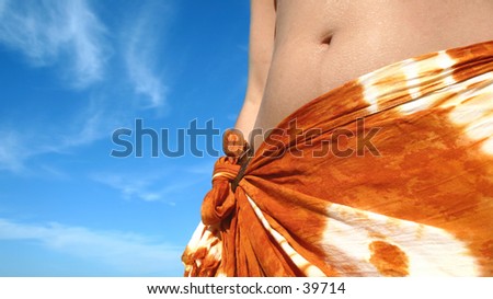 A young woman wearing a sarong against a blue sky.