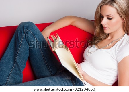 Beautiful woman reading book on couch