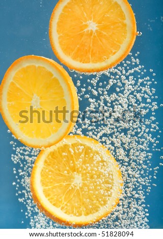 Fresh orange dropped into water with bubbles