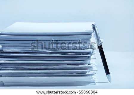 a pen near stack of paper