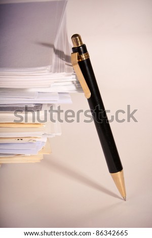 a pen near stack of paper