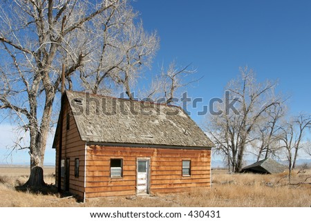 an abandoned, run down home in rural wyoming. broken-down shack in the background.