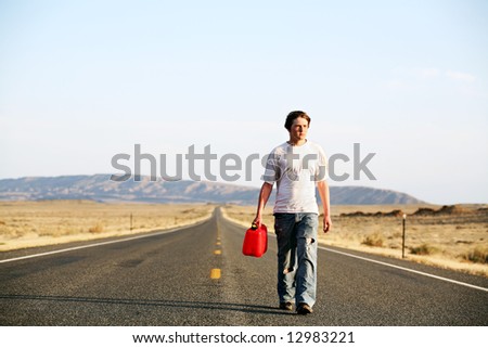 out of gas - teenager male walking down rural highway with empty red gas can