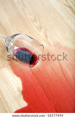 red wine spilled from glass on hardwood floor