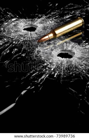 bullet holes in glass with bullet - broken glass isolated on black