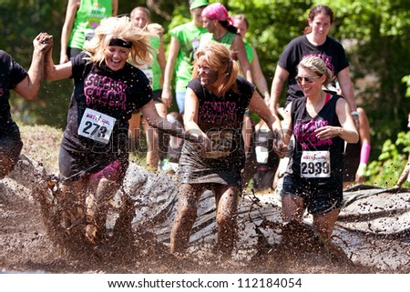 ATLANTA, GA , USA - APRIL 28, 2012:  A group of unidentified women competing in the Dirty Girl Mud Run, splash through mud as they near the finish line of the women only race on April 28, 2012 in Atlanta.