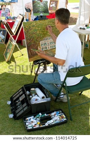 SUWANEE, GA - MAY 19:  An artist paints on canvas in his exhibitor booth at the Arts In The Park Festival, an outdoor event held at Suwanee Town Park on May 19, 2012 in Suwanee, GA.