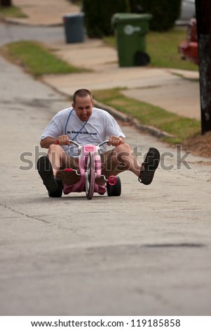 ATLANTA, GA - SEPTEMBER 29:  An unidentified man rides a child\'s big wheel down a hilly street, as part of the \