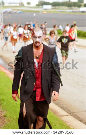 ATLANTA, GA - JUNE 8:  A male zombie wearing a tattered suit, emerges from the crowd after chasing runners in the Zombie Run on June 8, 2012 in Atlanta, GA.