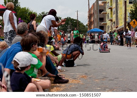 ATLANTA, GA - AUGUST 3:  An unidentified child steers a toy car down a hilly street in the Cool Dads Rock Soap Box Derby, at the Old 4th Ward Park on August 3, 2013 in Atlanta.
