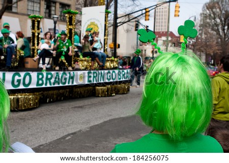 ATLANTA, GA - MARCH 15:  A woman wearing a green wig watches as a parade float passes by at the annual St. Patrick\'s parade, on March 15, 2014 in Atlanta, GA.