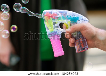 ATLANTA, GA - MARCH 15:  A man\'s hand uses a bubble gun to blow bubbles at the St. Patrick\'s Day parade on Peachtree Street, on March 15, 2014 in Atlanta, GA.