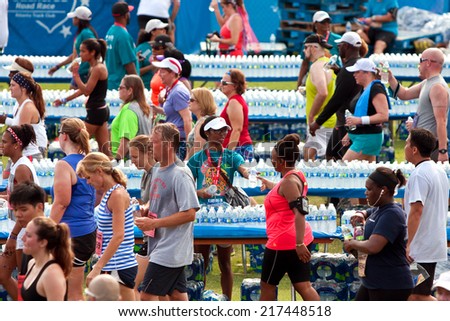 ATLANTA, GA - JULY 4:  Volunteers hand out water bottles to exhausted runners in the aftermath of the Peachtree Road Race 10K on July 4, 2014 in Atlanta, GA.