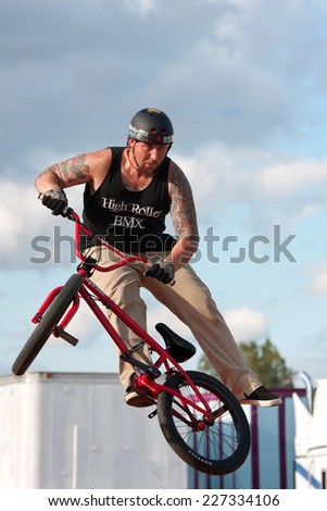 HAMPTON, GA - SEPTEMBER 27:  A young man with the High Roller BMX club spins his bike in midair while performing a BMX stunt at the Georgia State Fair on September 27, 2014 in Hampton, GA.