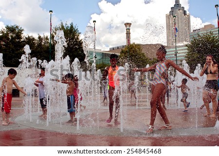 ATLANTA, GA - SEPTEMBER 6: A group of kids gets soaking wet while playing in the fountain at Centennial Park on September 6, 2014 in Atlanta, GA.