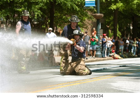 ATLANTA, GA - MAY 2:  Firemen aim a fire hose at a target in a fireman muster competition between local area fire departments, at the Fire In The Fourth festival on May 2, 2015 in Atlanta, GA.