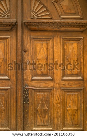old wooden gate decorated with pattern carved in wood, with handle and lock