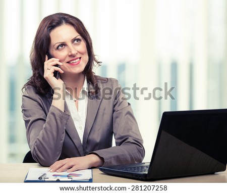 Middle-age business woman talking on the mobile phone in office. Portrait of smiling business woman. Toned photo
