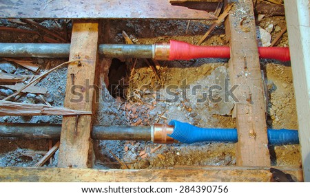 Cold and hot water pipes under a broken wood floor