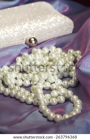 Beautiful pearl necklace and clutch bag on a beautiful transparent organza fabric