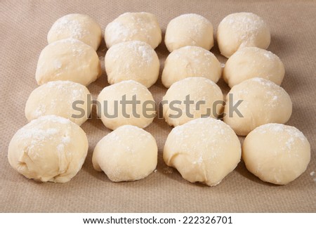 Small balls of dough with flour for pizza or cakes and scones lying on the baking paper. Shallow depth of field