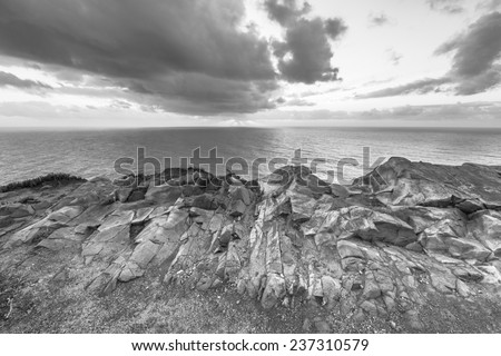 Dramatic sunset rays through a cloudy dark sky over the ocean. Black and white