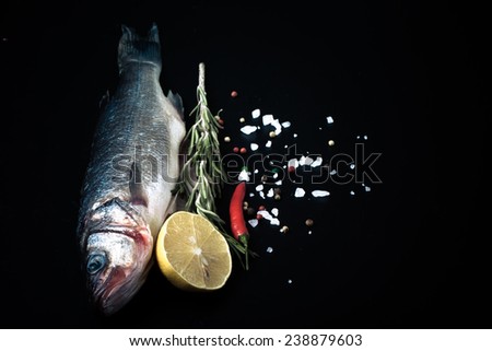 Fresh sea fish lying on dark background with spices. Space for text