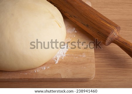 dough on a board and rolling pin with flour dusting. Close-up