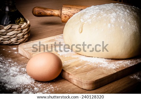 dough on a board with flour. olive oil, eggs, rolling pin