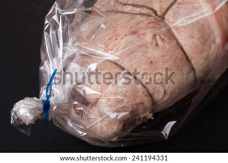 Raw meat with rope in the package on a black background.