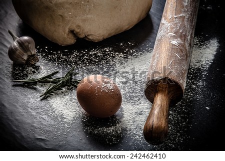 dough on a black board with flour. eggs, rolling pin, garlic. Tinted