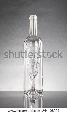 Empty bottle and glass with a pop of transparent glass. Standing each other. With Reflection