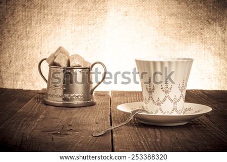 Cup of coffee and brown sugar in a vintage metal sugar-bowl on a wooden table. Toned.
