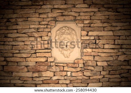 Wall of natural stones with bas-relief of lion. Toned.