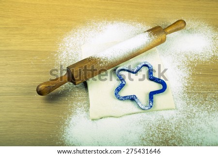Set for home baking on a light wooden table with flour. Rolling pin, baking form, dough. Toned.