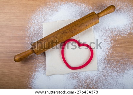 Set for home baking on a light wooden table with flour. Rolling pin, baking form, dough.