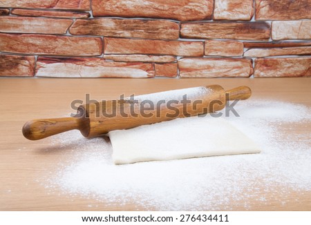 Set for home baking on a light wooden table with flour. Rolling pin and dough.