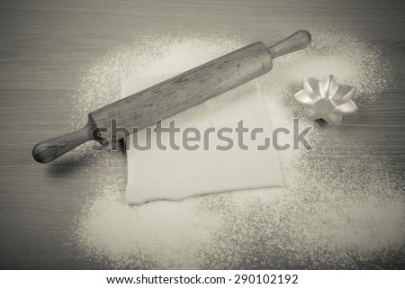 Rolling pin, dough and baking form on a light wooden table with flour. Toned.