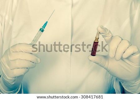 Professional doctor holding a syringe and an empty ampoule of medicine