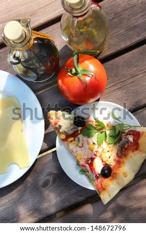 Piece of pizza in the summer garden table with olive oil and vinegar sauce