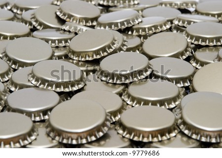 A pile of gold colored beer bottle caps all facing upward