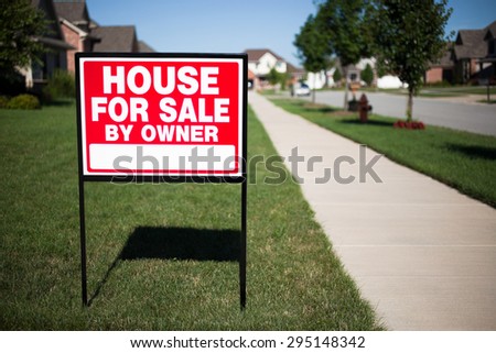 House For Sale By Owner Sign in a front yard of a home