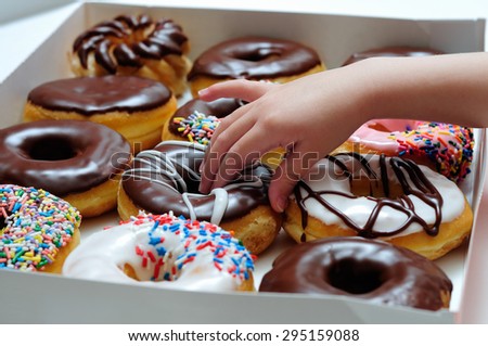 Picture of doughnut box with a child\'s hand taking a donut