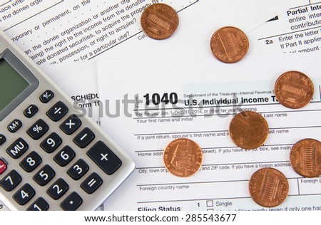 Federal tax form 1040 on a desk with a calculator and pennies