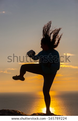 Silhouette of the girl boxer on background sunrise